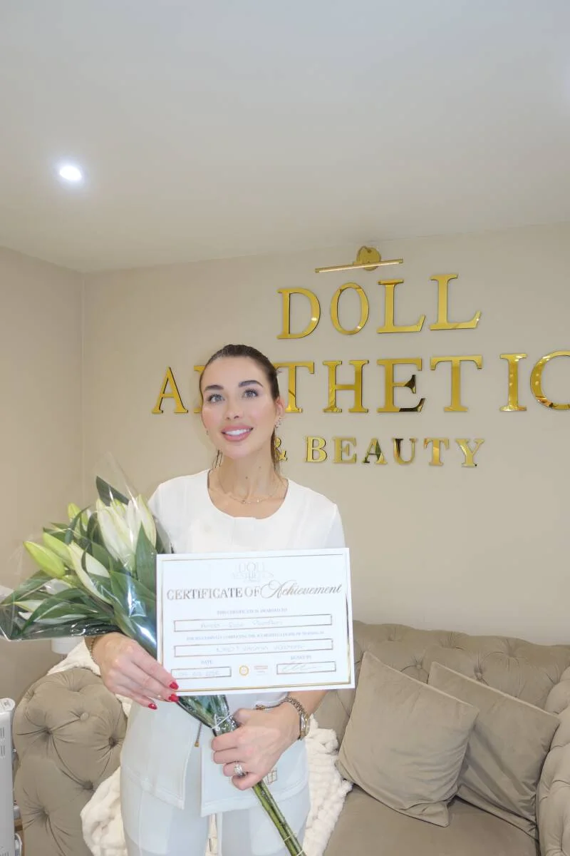 Doll Academy graduate holding her certificate and flowers in the West Mersea clinic