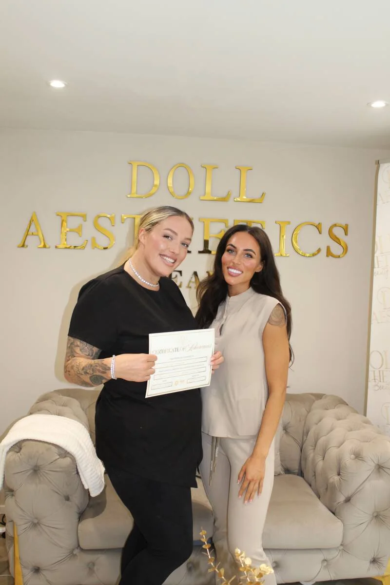 Two Doll Academy graduates holding their certificates on completion day