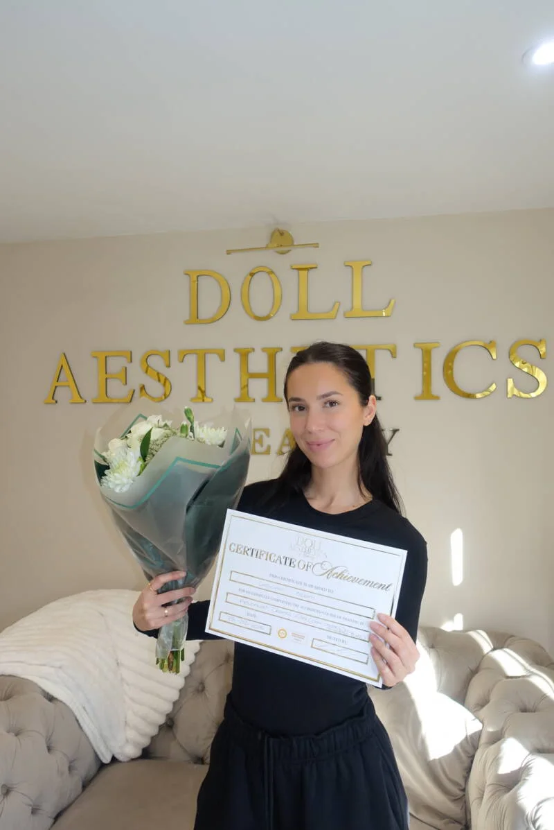 Doll Academy graduate holding her certificate and flowers in the West Mersea clinic
